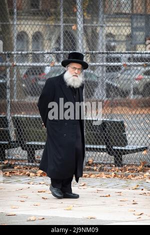 Ein orthodoxer jüdischer Mann in einem langen schwarzen Mantel geht auf der Bedford Ave. In Brooklyn in einem sehr jüdischen Viertel. Stockfoto