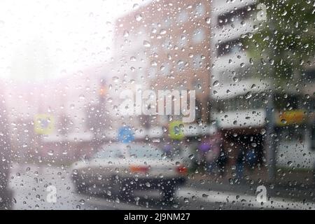 Regentropfen auf der Windschutzscheibe auf Stadtstraße Hintergrund Makrofotografie Stockfoto