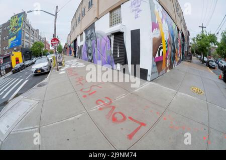 Eine Fischauge-Ansicht einer Ecke in Bushwick, Brooklyn, mit Street Art und einer Botschaft auf dem Boden, die besagt, dass Liebe die Antwort ist. Stockfoto