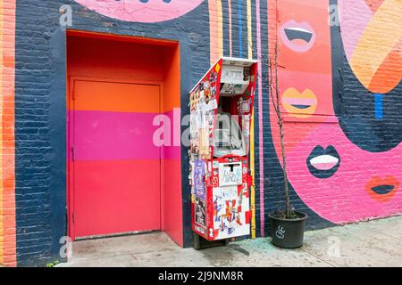 Eine Collage aus Aufklebern, Tags, Hinweisen und Graffiti auf einem Geldautomaten im Freien in der Jefferson Street in Bushwick, Brooklyn, der Outdoor-Kunsthauptstadt von NYC. Stockfoto