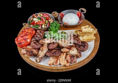 Türkische Küche gemischter Kebab. Shish Kebab, Shaverma, gegrilltes Hähnchen. Gerichte der orientalischen Küche, die auf Pita-Brot liegen und mit Gemüse und Gemüse dekoriert sind Stockfoto