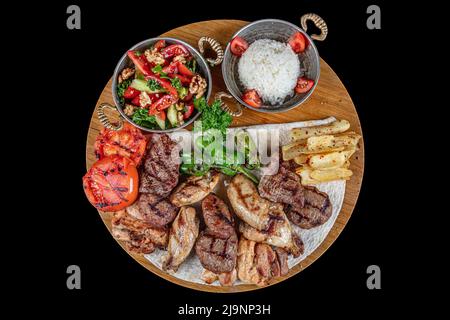 Türkische Küche gemischter Kebab. Shish Kebab, Shaverma, gegrilltes Hähnchen. Gerichte der orientalischen Küche, die auf Pita-Brot liegen und mit Gemüse und Gemüse dekoriert sind Stockfoto