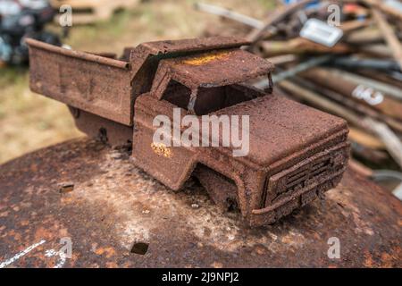 Rostiger alter Spielzeugkipper, der aus Metall hergestellt wurde und lange Zeit im Boden begraben lag, bedeckt mit Schlamm-Rost und fehlenden Rädern Stockfoto