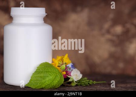 Kunststoffbehälter für medizinische Pillen, Nahrungsergänzungsmittel auf natürlichem Hintergrund. Frische Blumen, Kräuter. Kräutervorbereitung Mockup. Stockfoto