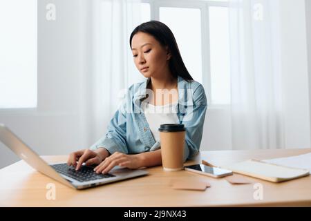 Fokussierte ernsthafte junge asiatische niedlich weibliche Geschäftsfrau Art Steuerbericht auf Laptop in hellen Büroinnenraum. Freiberufliche Mitarbeiter arbeiten zu Hause. Dame Stockfoto