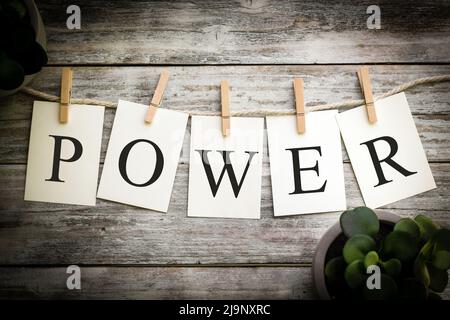 Eine Reihe von gedruckten Karten, die das Wort POWER auf einem alten Holzhintergrund schreiben. Stockfoto