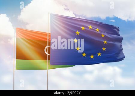 Sonniger blauer Himmel und Flaggen der europäischen Union und libyens Stockfoto