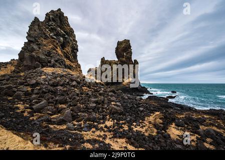 Panoramablick auf die beeindruckenden Lóndrangar Basaltfelsen an der Küste bei Malarrif, Snæfellsjökull Nationalpark, Snæfellsnes, Island Stockfoto