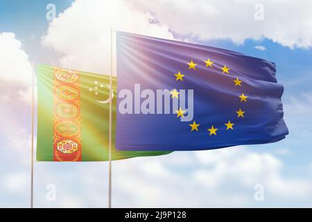 Sonniger blauer Himmel und Flaggen der europäischen Union und turkmenistans Stockfoto