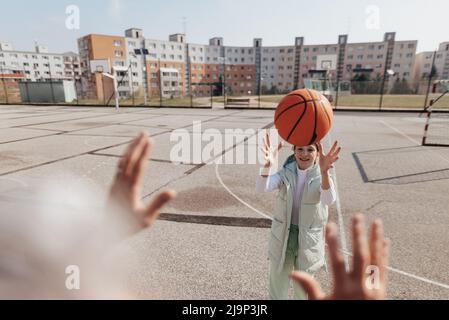 Glücklicher Vater und Tochter im Teenageralter spielen draußen am Hof Basketball. Stockfoto