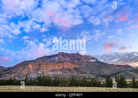 sonnenaufgangswolken über dem Burgriff entlang der felsigen Bergfront in der Nähe von augusta, montana Stockfoto