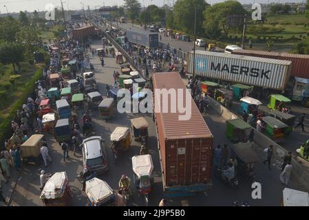 Pakistanische Pendler versuchen, sich über eine Brücke über den Ravi-Fluss auf einer Straße zu bewegen, die von den lokalen Behörden teilweise mit Containern gesperrt ist, um die Mobilität vor dem in Islamabad geplanten Sit-in durch den ehemaligen pakistanischen Premierminister Imran Khan der pakistanischen Partei Tehreek-e-Insaf (PTI) in Lahore zu behindern. Pakistans wichtigste Oppositionspartei unter der Führung des kürzlich gestürzten Premierministers Imran Khan beschuldigte die Polizei, Hunderte ihrer Anhänger in Razzien zu verhafteten, die Anfang Dienstag vor einem großen Sit-in begannen, das vom ehemaligen Führer, hochrangigen Parteimitgliedern und Polizeiquellen geplant wurde. (Foto von Rana Sajid Huss Stockfoto