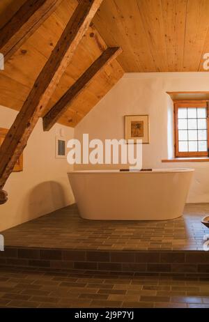 Hauptbadezimmer mit freistehender Badewanne auf zweigeschossigem Keramikfliesen-Boden im alten, ca. 1780 erdsteinbemalten Haus. Stockfoto