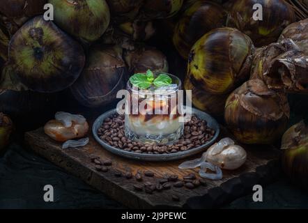 Frisch geschnittene Toddy-Palme in frischem Toddy-Palmsaft mit zerdrücktem Eis, gemischtem Espresso-Kaffee und Minzblättern. Zweilagiger Cocktail mit Minzblättern in gla Stockfoto