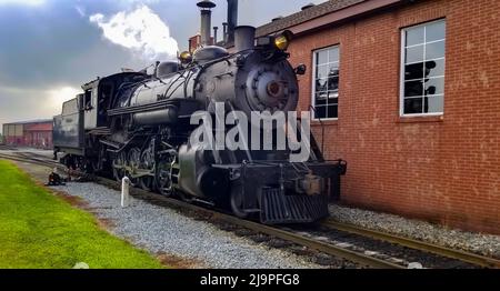 Eine restaurierte Dampfmaschine, die sich bereit für den Service macht, Rauch und Dampf an einem wolkigen Sommertag bläst Stockfoto