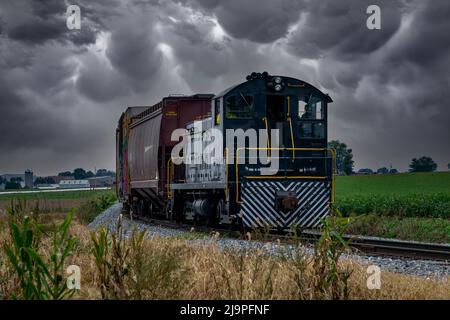 Ronks, Pennsylvania, Oktober 2020 - Blick auf einen Diesel-Güterzug, der auf einem einzigen Track mit Graffiti-Autos unterwegs ist, während ein Sturm sich nähert. Stockfoto