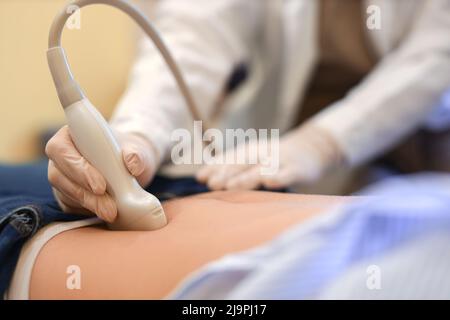 Junge Schwangere, die in einer modernen Klinik Ultraschall-Untersuchung unterzogen wird, Nahaufnahme Stockfoto