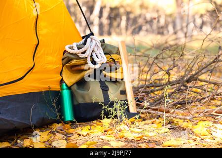 Touristenrucksack mit Überlebenskit in der Nähe des Zeltes im Wald Stockfoto