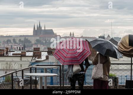 Prag, Tschechische Republik. 24.. Mai 2022. Touristen, die Regenschirme tragen, beobachten das Panorama der Stadt und der Prager Burg von einer Dachterrasse aus bei Regenwetter in Prag. Kredit: SOPA Images Limited/Alamy Live Nachrichten Stockfoto