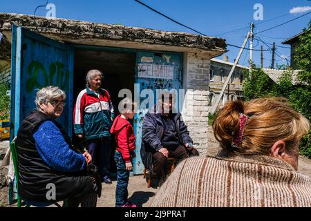 Menschen sitzen vor einem Bunker, wo sie in den Außenbezirken der Stadt verlassen. Lysychansík, Region Luhansk. 23. Mai 2022 Lysytschansk ist eine langgestreckte Stadt am rechten Ufer des Donezflusses in der Region Luhansk. Die Stadt ist Teil eines Ballungsraums, zu dem Severodonetsk und Rubizhne gehören; die drei Städte bilden zusammen einen der größten Chemiekomplexe der Ukraine. Die Stadt liegt etwa 7 km von der Front entfernt, und russische Truppen ziehen auf sie zu, die Stadt, wie Severodonetsk, ist fast isoliert. Die Russen versuchen, die Hauptstraße zu besetzen, die Lysytschansk mit Kramatorsk verbindet Stockfoto