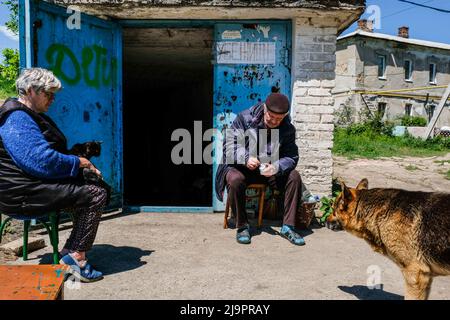 Menschen sitzen vor einem Bunker, wo sie in den Außenbezirken der Stadt verlassen. Lysychansík, Region Luhansk. 23. Mai 2022 Lysytschansk ist eine langgestreckte Stadt am rechten Ufer des Donezflusses in der Region Luhansk. Die Stadt ist Teil eines Ballungsraums, zu dem Severodonetsk und Rubizhne gehören; die drei Städte bilden zusammen einen der größten Chemiekomplexe der Ukraine. Die Stadt liegt etwa 7 km von der Front entfernt, und russische Truppen ziehen auf sie zu, die Stadt, wie Severodonetsk, ist fast isoliert. Die Russen versuchen, die Hauptstraße zu besetzen, die Lysytschansk mit Kramatorsk verbindet Stockfoto