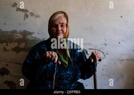 Eine alte Frau, die am Eingang des Bunkers sitzt, wo sie am Stadtrand abfahren. Lysychansík, Region Luhansk. 23. Mai 2022 Lysytschansk ist eine langgestreckte Stadt am rechten Ufer des Donezflusses in der Region Luhansk. Die Stadt ist Teil eines Ballungsraums, zu dem Severodonetsk und Rubizhne gehören; die drei Städte bilden zusammen einen der größten Chemiekomplexe der Ukraine. Die Stadt liegt etwa 7 km von der Front entfernt, und russische Truppen ziehen auf sie zu, die Stadt, wie Severodonetsk, ist fast isoliert. Die Russen versuchen, die Hauptstraße zu besetzen, die Lysychan verbindet Stockfoto