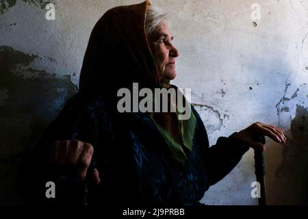 Eine alte Frau, die am Eingang des Bunkers sitzt, wo sie am Stadtrand abfahren. Lysychansík, Region Luhansk. 23. Mai 2022 Lysytschansk ist eine langgestreckte Stadt am rechten Ufer des Donezflusses in der Region Luhansk. Die Stadt ist Teil eines Ballungsraums, zu dem Severodonetsk und Rubizhne gehören; die drei Städte bilden zusammen einen der größten Chemiekomplexe der Ukraine. Die Stadt liegt etwa 7 km von der Front entfernt, und russische Truppen ziehen auf sie zu, die Stadt, wie Severodonetsk, ist fast isoliert. Die Russen versuchen, die Hauptstraße zu besetzen, die Lysychan verbindet Stockfoto