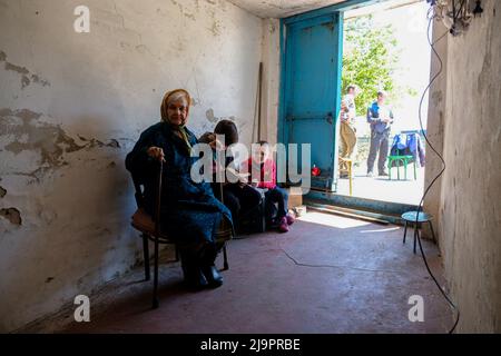 Eine alte Frau sitzt neben zwei Kindern am Eingang des Bunkers, wo sie in den Außenbezirken der Stadt abreisen. Lysychansík, Region Luhansk. 23. Mai 2022 Lysytschansk ist eine langgestreckte Stadt am rechten Ufer des Donezflusses in der Region Luhansk. Die Stadt ist Teil eines Ballungsraums, zu dem Severodonetsk und Rubizhne gehören; die drei Städte bilden zusammen einen der größten Chemiekomplexe der Ukraine. Die Stadt liegt etwa 7 km von der Front entfernt, und russische Truppen ziehen auf sie zu, die Stadt, wie Severodonetsk, ist fast isoliert. Die Russen versuchen, die Hauptstraße zu besetzen Stockfoto