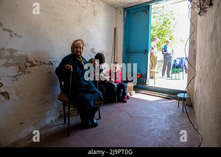 Eine alte Frau sitzt neben zwei Kindern am Eingang des Bunkers, wo sie in den Außenbezirken der Stadt abreisen. Lysychansík, Region Luhansk. 23. Mai 2022 Lysytschansk ist eine langgestreckte Stadt am rechten Ufer des Donezflusses in der Region Luhansk. Die Stadt ist Teil eines Ballungsraums, zu dem Severodonetsk und Rubizhne gehören; die drei Städte bilden zusammen einen der größten Chemiekomplexe der Ukraine. Die Stadt liegt etwa 7 km von der Front entfernt, und russische Truppen ziehen auf sie zu, die Stadt, wie Severodonetsk, ist fast isoliert. Die Russen versuchen, die Hauptstraße zu besetzen Stockfoto