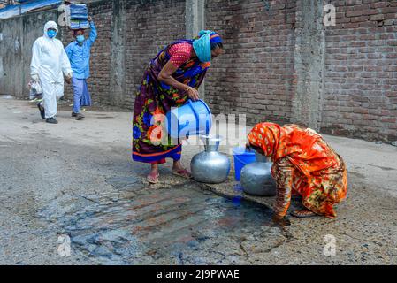 Frauen sammeln Trinkwasser von einem Wasserrohrbruch auf einer beschädigten Straße in Dhaka. Stockfoto