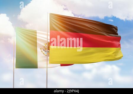 Sonniger blauer Himmel und Flaggen von deutschland und mexiko Stockfoto
