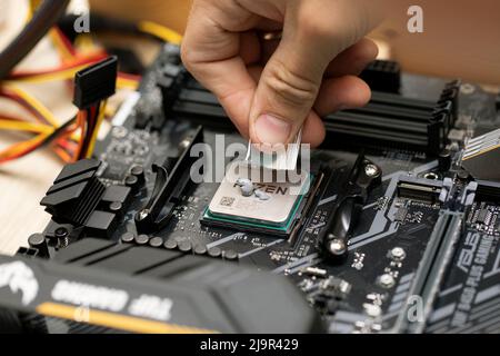 Techniker, der die Wärmeleitpaste auf die CPU-Abdeckung des Mikroprozessorchips auf dem Tuf Gaming B450 plus Mainboard aufsetzt. Russland, 17.08.2021 Stockfoto