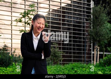 Geschäftsfrau, die lachend in einem Park telefoniert Stockfoto