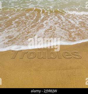 Konzeptbild - um Stress abzuwaschen, indem man einen Urlaub macht, während die Wellen an einem Sandstrand das Wort „Probleme“ wegwaschen. Stockfoto