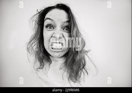 Nahaufnahme Porträt einer verrückten Frau in Zwangsjacke auf weißem Hintergrund. Monochrom. Stockfoto