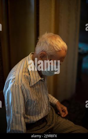Alter Mann in Maske. Älterer Mann in der Wohnung. Rentner im Haus. Grizzled man. Mann von 90 Jahren. Stockfoto