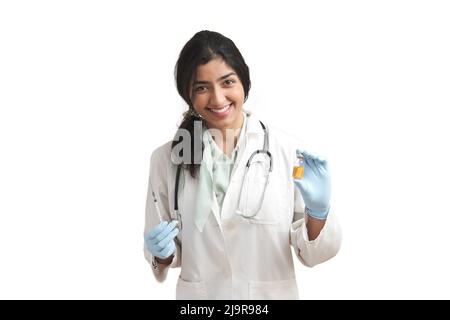 Junge venezolanische Ärztin mit einer Spritze und einem Fläschchen, isoliert. Stockfoto