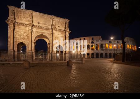 Der Konstantinsbogen und das Kolosseum bei Nacht in der Stadt Rom, Italien. Blick von der Piazza del Arco di Costantino. Stockfoto