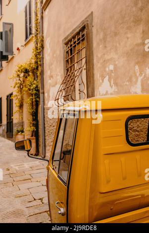 Ein typisch italienischer Dreiradler in den engen mittelalterlichen Gassen von Castiglione della Pescaia, einem alten Dorf an der toskanischen Küste Stockfoto