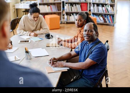 Moderne Familie von schwarzen Migranten, die Sprachunterricht in der internationalen Schule besuchen und dem Lehrer zuhören Stockfoto