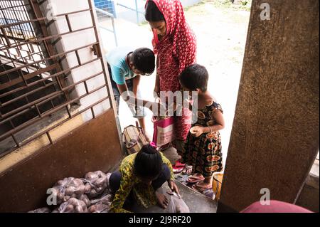 Die Regierung von Westbengalen hat staatliche Schulen angewiesen, während der Sommerferien Mittagsessen an Eltern von Schülern zu verteilen, damit den bedürftigen Kindern das Programm nicht entzogen wird. In der Mitteilung hieß es, dass jeder Schüler 2 kg Reis, 2 kg Kartoffeln, 250 Gramm Zucker, 250 Gramm Hülsenfrüchte und ein Stück Seife erhalten würde. So kamen die Schüler in den Sommerferien an eine Grundschule, um ihre Essensartikel zu holen, und einige von ihnen helfen auch, Lebensmittel im Nabin Nagar, Westbengalen, zu geben. (Foto von Soumyabrata Roy/Pacific Press) Stockfoto