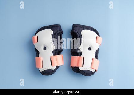 Draufsicht des Rollschuppen-Schutzausrüstung-Sets - Handgelenkpolster in rosa Farben. Blauer Hintergrund flach lag Stockfoto