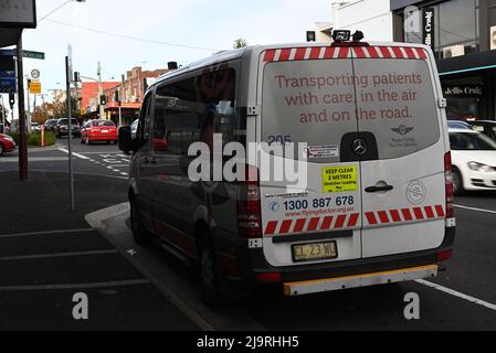 Hinter einem Krankenwagen des Royal Flying Doctor Service, der an der belebten Einkaufsstraße Centre Rd mit Geschäften und Verkehr im Hintergrund geparkt ist Stockfoto