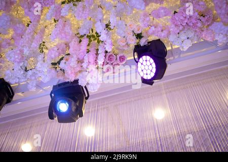 RGBW LED beweglicher Kopfstrahl und Wasch-Bühnenbeleuchtung im Veranstaltungssaal, der mit Blumen dekoriert ist. Stockfoto