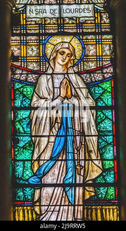 Glasmalerei unserer Lieben Frau von Lourdes, Wallfahrtskirche Maria Auxiliadora, Punta Arenas, Chile. Unsere Frau ist die Jungfrau Maria, die 1858 in Lourdes Fran erschienen ist Stockfoto