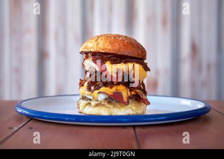 Ein großer großer großer Hamburger, Burger oder Cheeseburger mit geräuchertem Fleisch trifft sich auf einem Teller Stockfoto