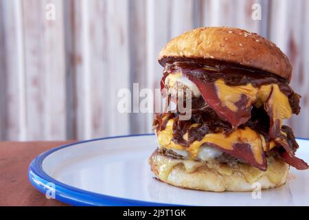 Ein großer großer großer Hamburger, Burger oder Cheeseburger mit geräuchertem Fleisch trifft sich auf einem Teller. Nahaufnahme mit Kopierbereich. Stockfoto