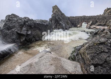 Portpatrick ist ein Dorf und eine Gemeinde an der Westküste der Rhin von Galloway Dumfries & Galloway. Der historische Torbogen widersteht dem Meer noch immer. Stockfoto