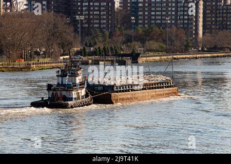 USA, New York City, Manhattan, Upper East Side. Barge schleppt Müll den East River hinunter, vom John Finley Walk aus gesehen Stockfoto