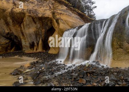 Der Wasserfall von Fall Creek fließt an stürmischen Tagen am Hug Point in der Nähe von Cannon Beach, Oregon, USA, in den Strand Stockfoto